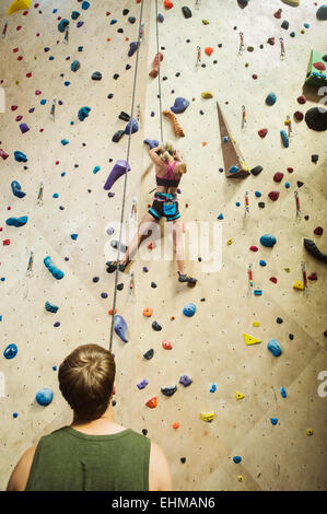 Uomo caucasico belaying scalatore all interno della parete di roccia Foto Stock