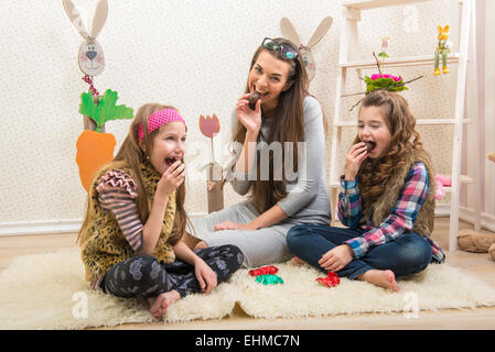 Pasqua - la madre e le sue due figlie mangiare uova di cioccolato Foto Stock