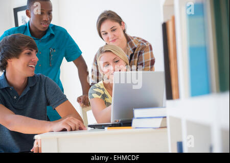 Gli adolescenti tramite computer portatile alla reception Foto Stock