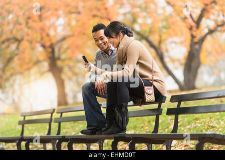 Matura mediante telefono cellulare su una panchina nel parco Foto Stock