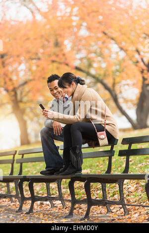 Matura mediante telefono cellulare su una panchina nel parco Foto Stock