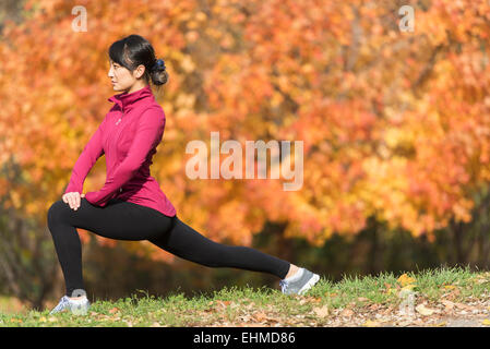 Asian runner stretching in posizione di parcheggio Foto Stock
