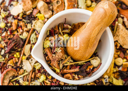 Mortaio e pestello impostato con tè alle erbe su bianco sullo sfondo di legno Foto Stock