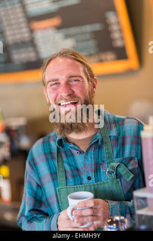 Server caucasica holding tazza di caffè nella caffetteria Foto Stock