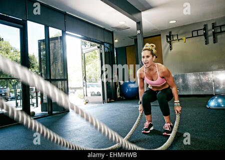 La donna caucasica lavoro fuori con corde in palestra Foto Stock