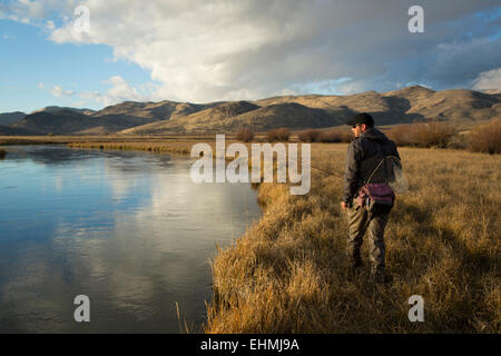 Uomo che trasportava forniture di pesca vicino al fiume Foto Stock