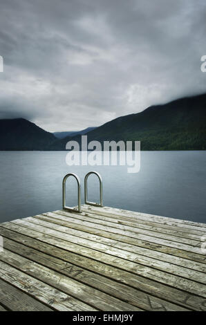 Scala sul molo in legno vicino ancora lago remoto Foto Stock