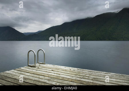 Scala sul molo in legno ancora al lago remoto Foto Stock