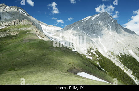 Picchi di montagna con la neve e di erba sotto il cielo blu Foto Stock