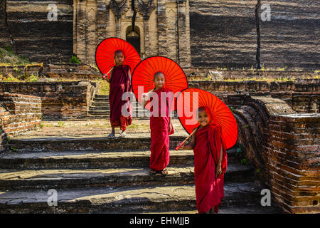 Monaci asiatici in piedi sotto gli ombrelloni vicino tempio storico, Mingun, Mandala, Myanmar Foto Stock