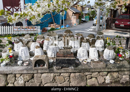 Kyoto, Giappone. Un santuario sul ciglio della strada sotto un albero ciliegio con rocce che rappresentano Jizo, protettore dei viaggiatori e dei bambini Foto Stock