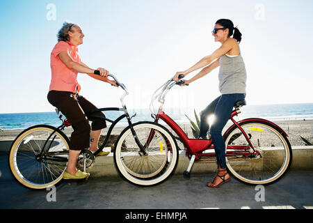 Caucasian madre e figlia di andare in bicicletta nei pressi della spiaggia Foto Stock