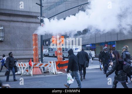 Il vapore proveniente da sotto la strada è una vista regolari nel centro di Manhattan tra l'edificio dell'ufficio. Foto Stock