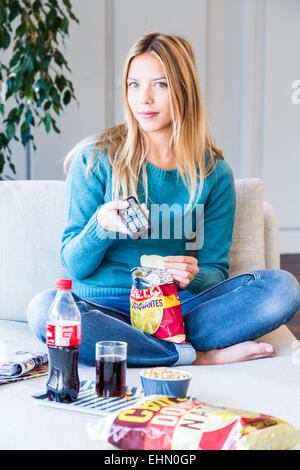 Donna snacking mentre si guarda la TV. Foto Stock