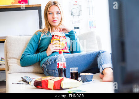 Donna snacking mentre si guarda la TV. Foto Stock