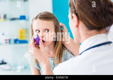 Medico di istruire una ragazza su come usare un inalatore per asmatici. Foto Stock