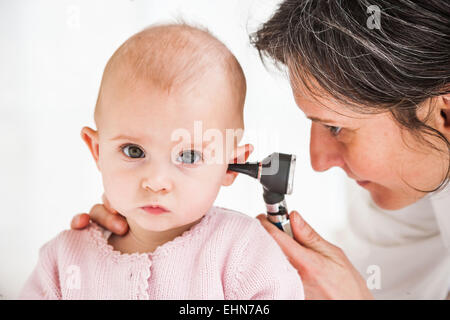 Pediatra esaminando l'orecchio di un 7-mese-vecchio bambina con un otoscopio. Foto Stock