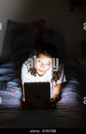 Ragazza adolescente utilizzando una tavoletta digitale di notte. Foto Stock