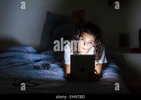 Ragazza adolescente utilizzando una tavoletta digitale di notte. Foto Stock