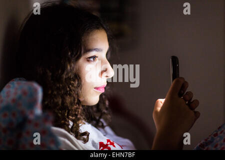 Ragazza adolescente utilizzando uno smartphone di notte. Foto Stock