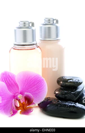 Bottiglie con prodotti cosmetici, pietre e orchidee Foto Stock