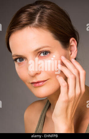 Donna l'applicazione di crema anti-rughe intorno agli occhi. Foto Stock
