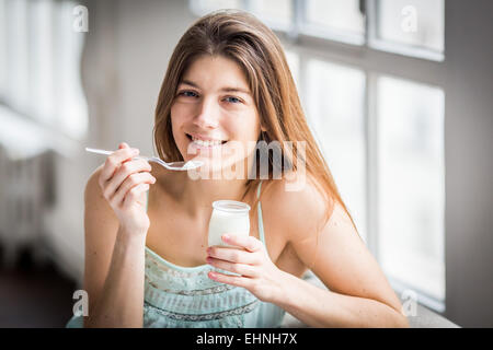 Donna di mangiare yogurt. Foto Stock