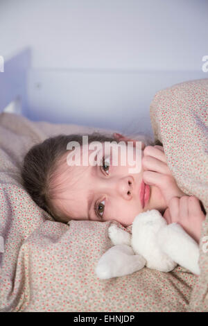 7 anno-vecchia ragazza sdraiato sul letto. Foto Stock