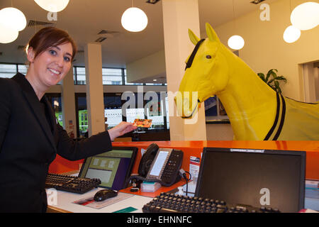 Liverpool, Merseyside, Regno Unito. 16th marzo 2013. La receptionist dell'hotel accoglie i visitatori del Grand National Event dell'Indigo Hotel. I dipendenti del Grand National sponsor Crabbies stanno progettando di soggiornare all'Hotel Indigo on Chapel Street durante il periodo dell'incontro di aprile. Oggi due cavalli gialli di dimensioni normali sono arrivati fuori dall'hotel come promozione per il Grand National Festival del Crabbie 2015 sulla 9th - 11th aprile 2015. Foto Stock