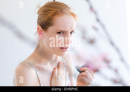 Donna che utilizza un inalatore per aerosol che contiene broncodilatatore per il trattamento di asma. Foto Stock