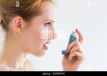 Donna che utilizza un inalatore per aerosol che contiene broncodilatatore per il trattamento di asma. Foto Stock