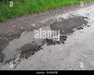 Buche in rottura di asfalto stradale del paese non marcati e pericoloso, Berkshire, Luglio Foto Stock