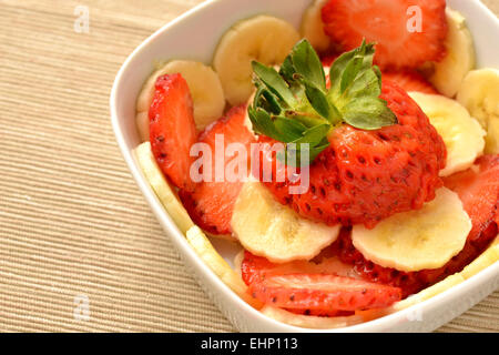 ​​Banana tagliati a fettine e le fragole in un recipiente bianco Foto Stock