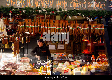 Una ragazza vende la carne e il formaggio in un mercatino di Natale di Budapest, Ungheria Foto Stock