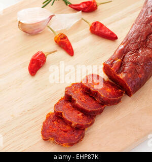 Un pezzo del chorizo spagnolo e alcune fette su un tagliere Foto Stock