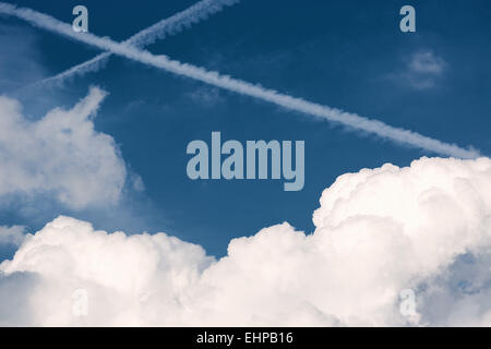 Due tracce di attraversamento da aerei nel cielo blu Foto Stock