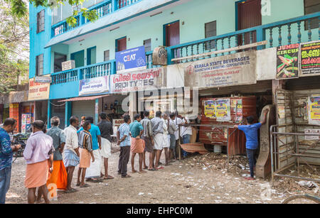 La gente locale coda pazientemente in fila per acquistare la birra, vino e altre bevande alcoliche in uno stato concesso in licenza shop in Cochin (Kochi), Kerala, nell India meridionale Foto Stock