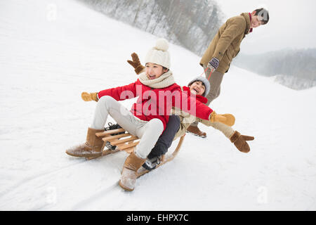 Giovane padre tirando i suoi figli su sled Foto Stock