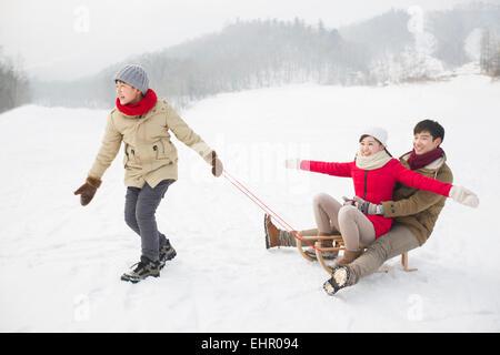 La famiglia felice giocando con slitta sulla neve Foto Stock