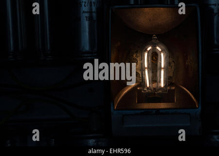 Il filamento incandescente di una 1000 lampada alogena al quarzo con scaglie di metallo e danni termici al riflettore e di erogatore di calore Foto Stock