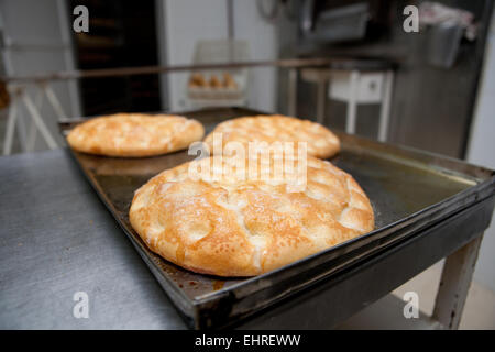 Processo di elaborazione della tradizionale dell'olio d'oliva spagnolo di frittelle. Baker prendendo sfornato fresco frittelle dal forno Foto Stock