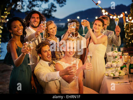 Gli ospiti dei matrimoni la tostatura con champagne durante il ricevimento di nozze in giardino