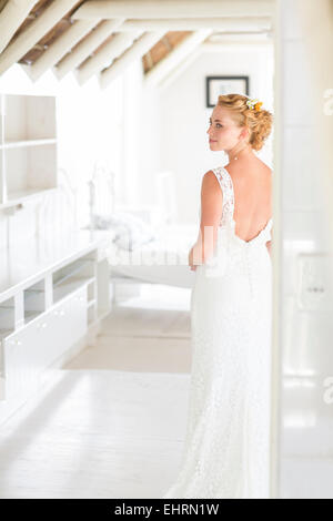 Giovane sposa in piedi nella soleggiata camera da letto Foto Stock