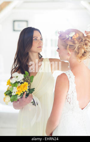 Damigella aiutando sposa con acconciatura in camera da letto Foto Stock