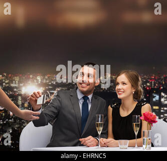 Coppia sorridente pagando per la cena con carta di credito Foto Stock