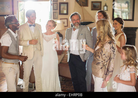 Coppia giovane con gli ospiti e champagne flauti al ricevimento di nozze Foto Stock