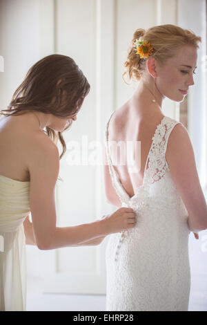 Damigella aiutando sposa con una medicazione in ambiente domestico Foto Stock