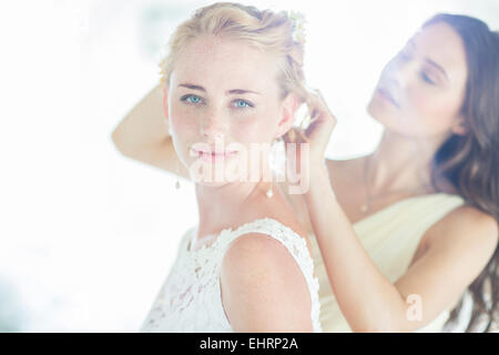 Damigella aiutando sposa con acconciatura in ambiente domestico Foto Stock