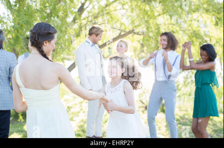 Damigella bambina e ballare durante il ricevimento di nozze nel giardino interno Foto Stock