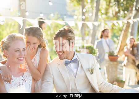 Damigella whispering alla sposa l orecchio durante il ricevimento di nozze nel giardino interno Foto Stock